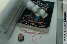 Right hand side of glass cabinet: Irigaray reader, Ikea paper tape measure, cork and string