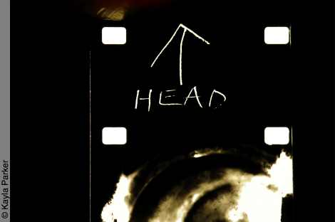 Beginning of 16mm filmstrip for Kayla Parker's film 'Hold', the first frame is scratched with the word HEAD and an arrow